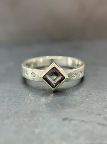 Silver ring with a green gemstone on a gray surface